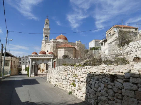 Тайбе тосгоны Гэгээн Георгийн ортодокс сүм: улаан бөмбөгөр оройтой цайвар чулуун сүм, өндөр хонхны цамхаг, урд нь чулуун хашаатай нарийн гудамж, цэнхэр тэнгэр